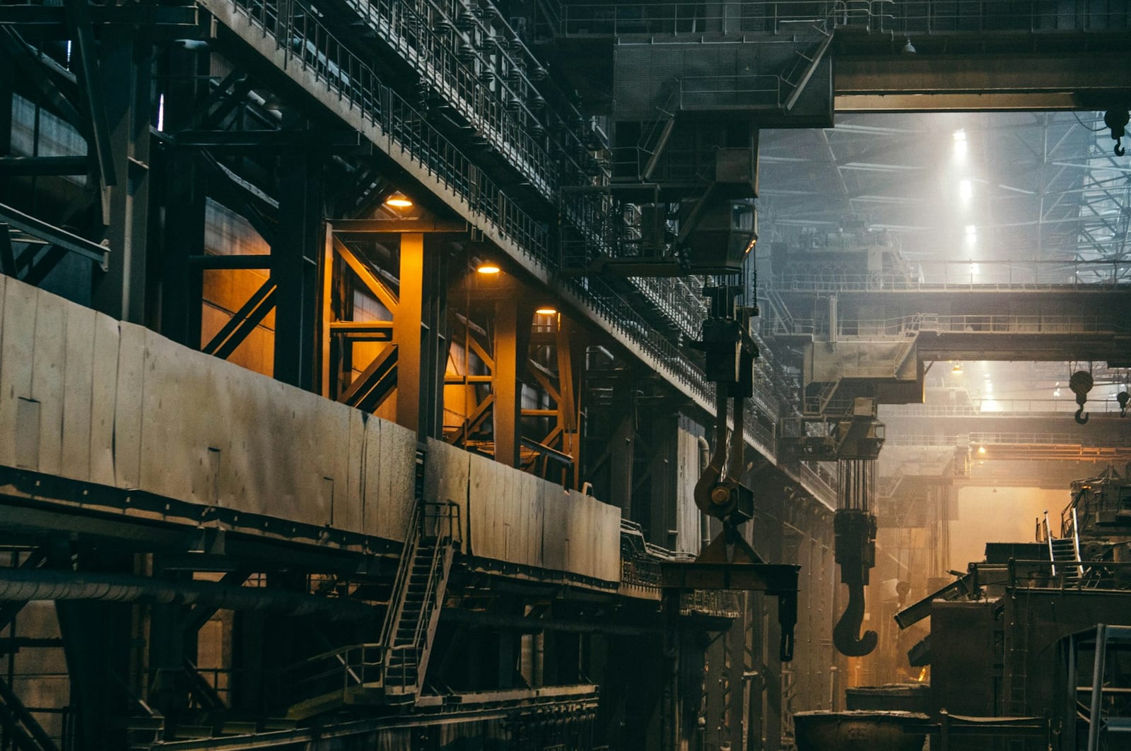 Interior of a large industrial factory hall with steel roof structure and machinery.